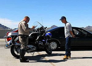 A motor officer writes a traffic ticket for a ...